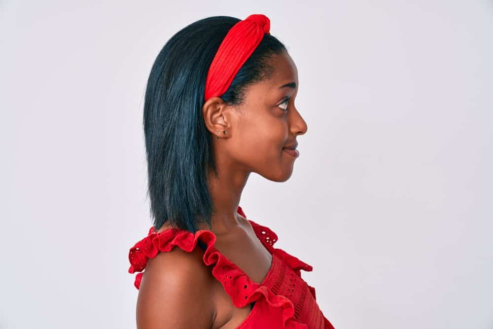 After using a hair dryer to eliminate frizz, a young African American woman was wearing a red headband.