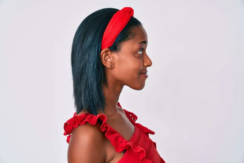 After using a hair dryer to eliminate frizz, a young African American woman was wearing a red headband.