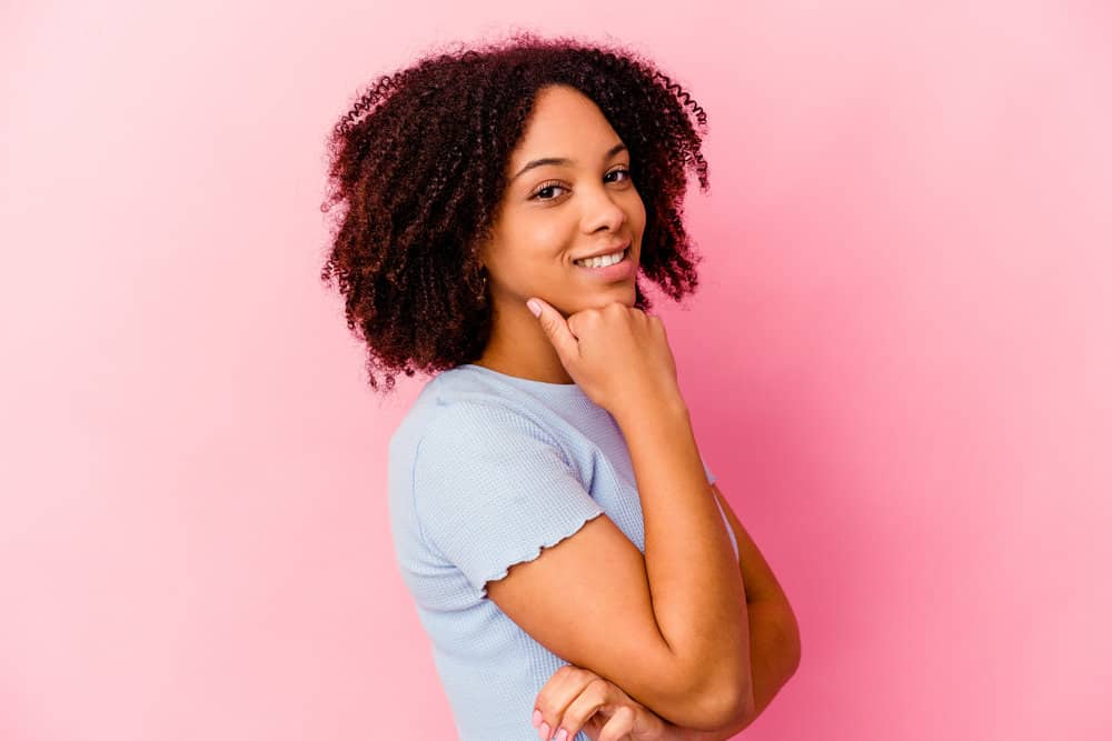 A young black female with dry hair has a curly hair type that's been styled after a deep conditioner.