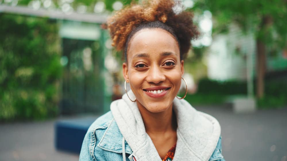 A young African American female with very dark hair wearing a bleached hair color in an updo ponytail style.