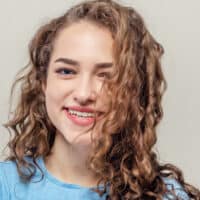 A beautiful young female with a wavy hair type wearing loose curls styled with styling cream.