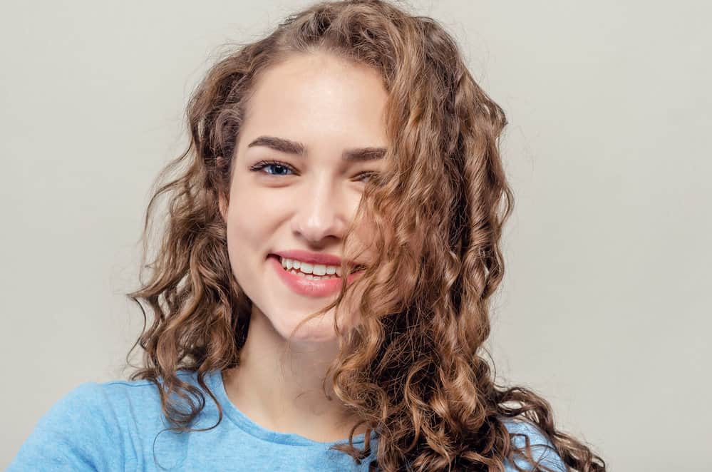 A beautiful young female with a wavy hair type wearing loose curls styled with styling cream.