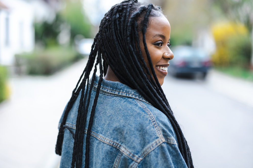 Lady wearing a beautiful lock style after using wax and hot water to her hair saturated to create dreadlocks.