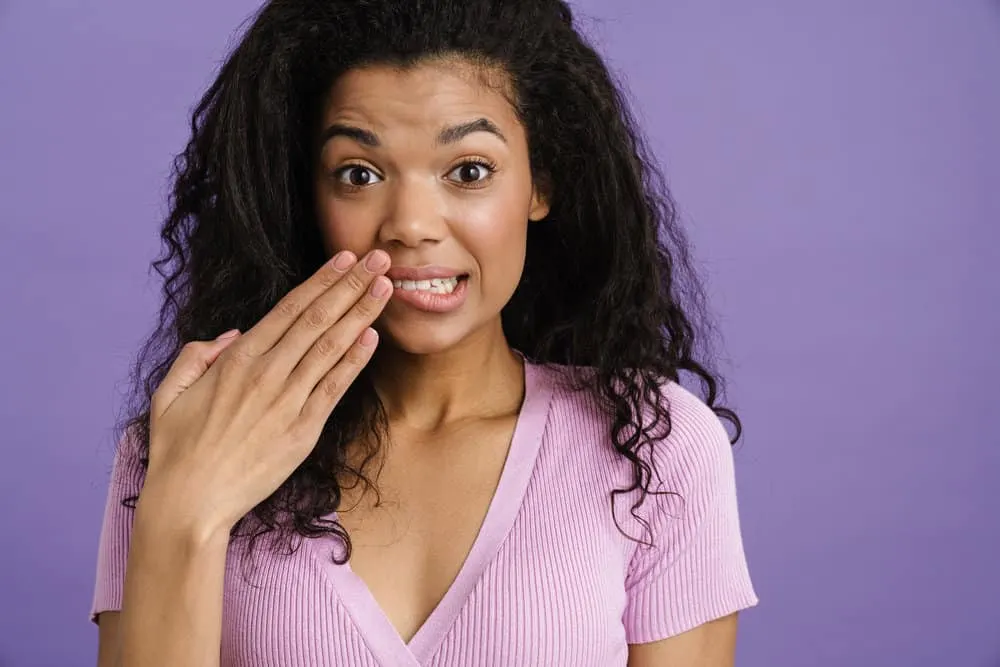 What Volume Developer Should I Use to Cover Gray Hair? | Gray Coverage 4 Young black woman covering her mouth while expressing surprise isolated over purple background