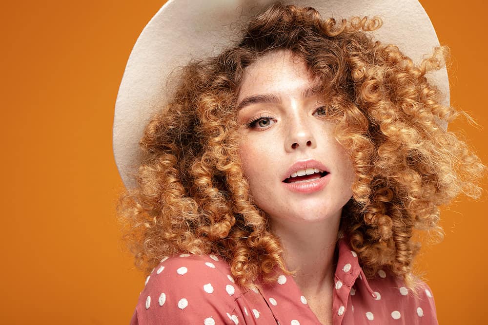 A cute female with natural freckles and curly hair strands underwent the bleaching process on her ginger curls.