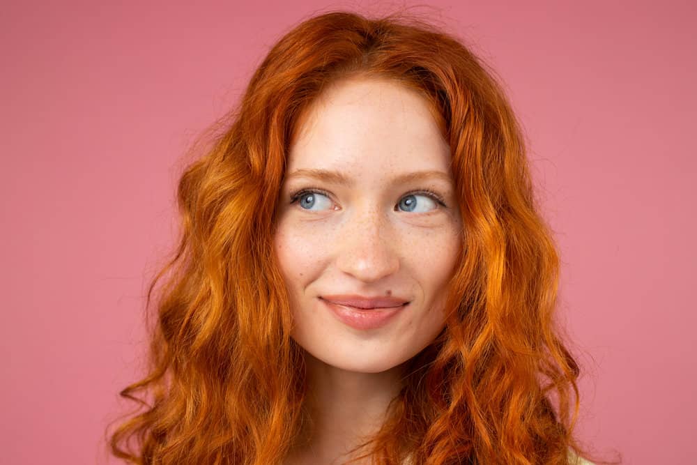A beautiful redhead female with a naturally wavy texture and loose curls styled with a curling iron and coconut oil.