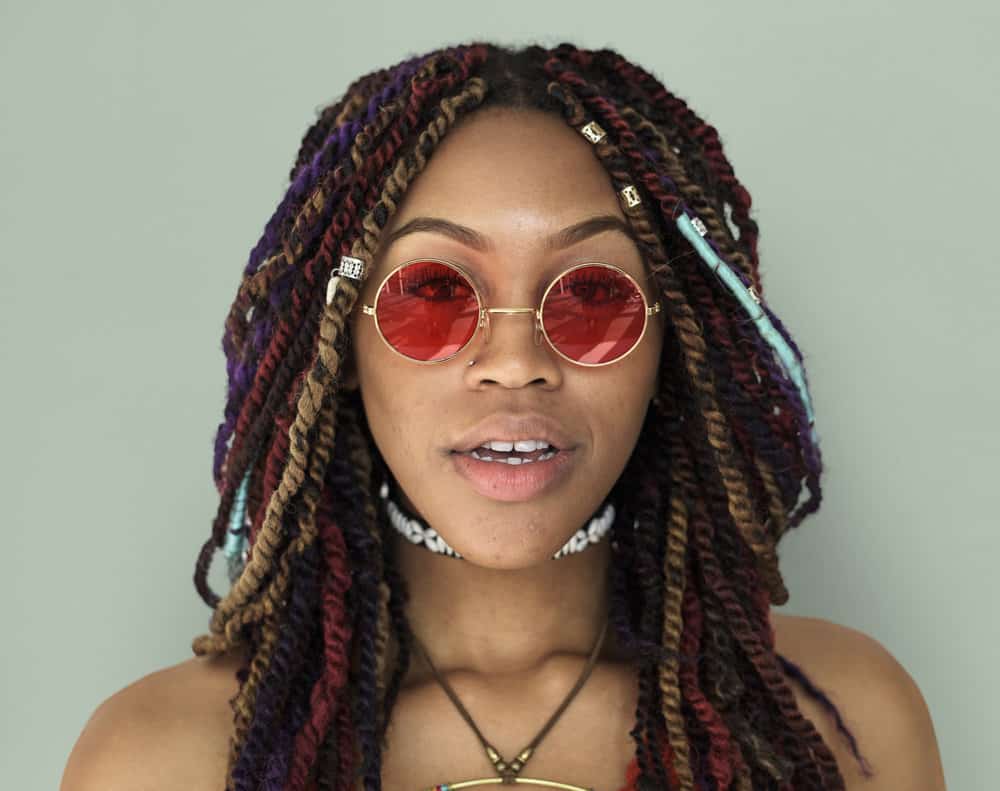 A lady with multi-colored synthetic braids has buck shots in the kitchen area of her hair along the nape of her neck.