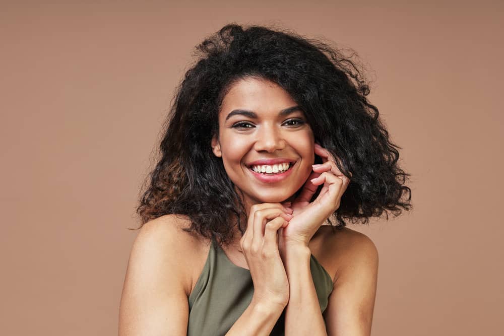 Young black lady with bouncy curls after wearing her hair straightened consistently for over 12 months.