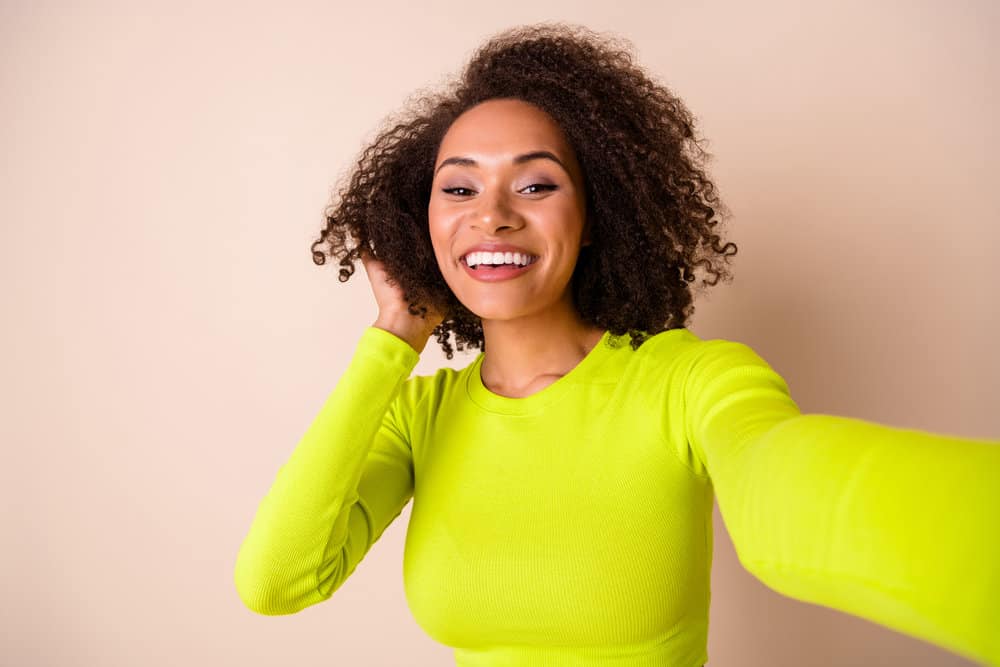 A nice woman with naturally curly hair washed with Planet shampoo filming a YouTube brand review of the product.