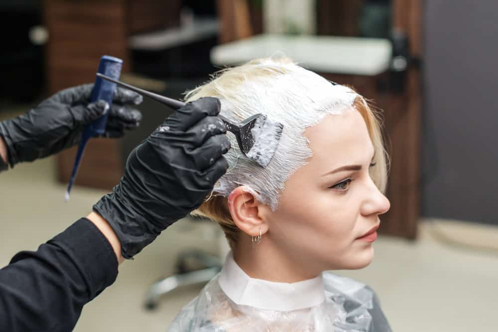 Young female with dye-stained skin after getting her naturally blonde 1B hair strands dyed professionally.