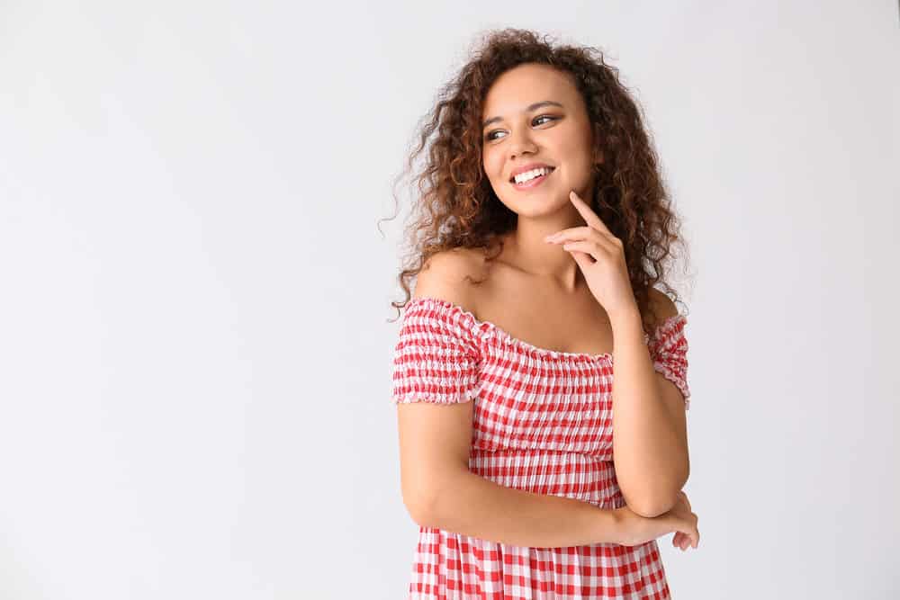 A black lady with great curl definition on her low porosity hair strands styled with a lightweight leave-in conditioner.