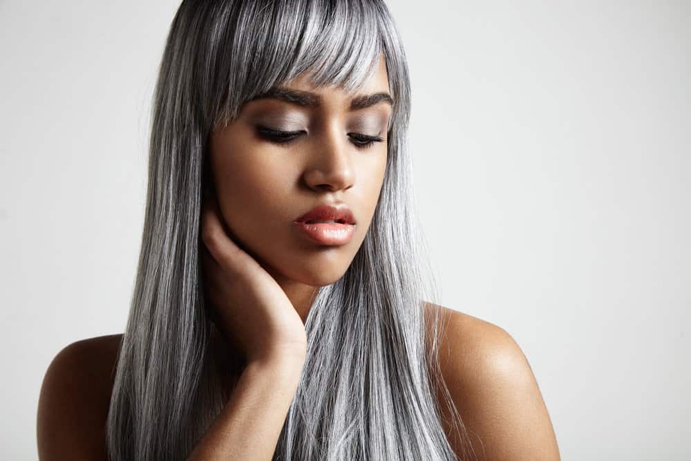 A light-skinned lady with dark hair after using purple shampoo on her gray hairs to aid in a gradual transition.