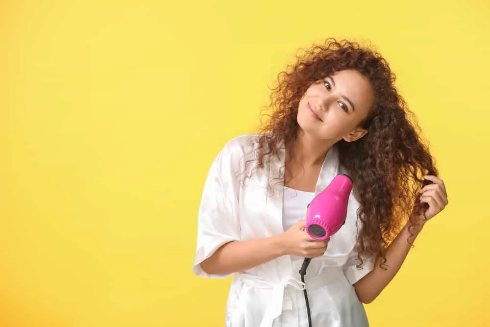 How Hot Does a Hair Dryer Get in Fahrenheit and Celsius 2 A cute young black female with thick hair using a hair dryer with adjustable heat settings and variable heating element.