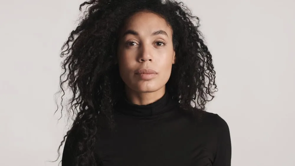 How to Thin Out Hair With and Without Thinning Shears 7 A beautiful female with shoulder-length hair growth styles her hair with natural oils to reduce frizz.