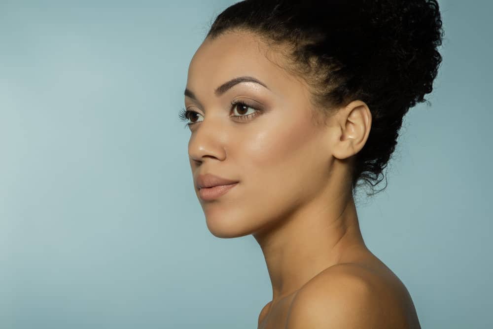 A black female with tangled hair used a wide tooth comb to detangle hair strands with olive oil and natural oils.