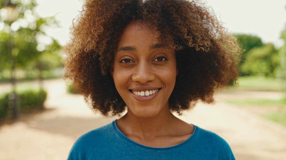 Young black girl with thick hair that is slightly wavy and curly wearing her coarse hair in an ombre style.