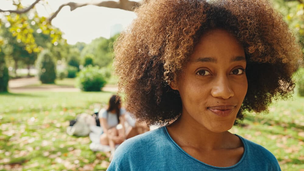 A middle-aged black woman with curly strands of hair showing off the natural texture of her kinky hair strands.