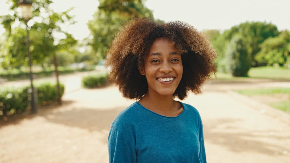 A black female with medium brown skin styled with a conditioning hair mask and coconut hair oil.