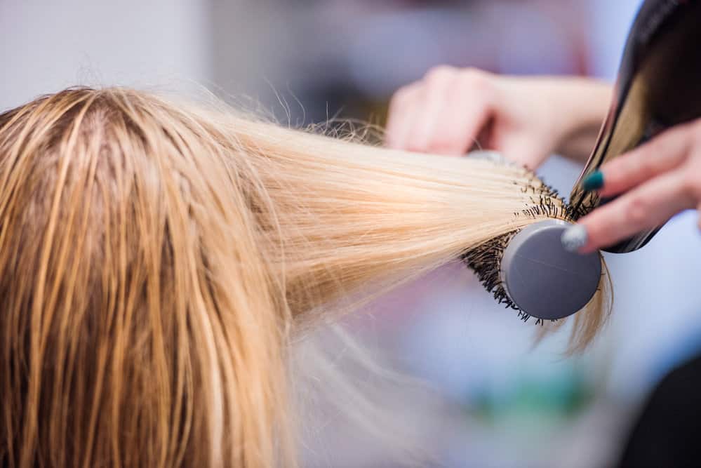 Professional stylist drying a client's with a hair dryer suitable for fine hair, coarse hair, and straight hair.