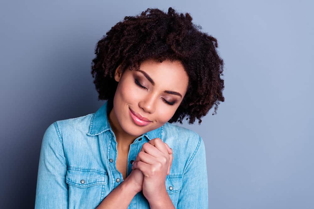 A cute young black girl lives in a dry environment (or dry climate) where her hair feels rough and brittle.