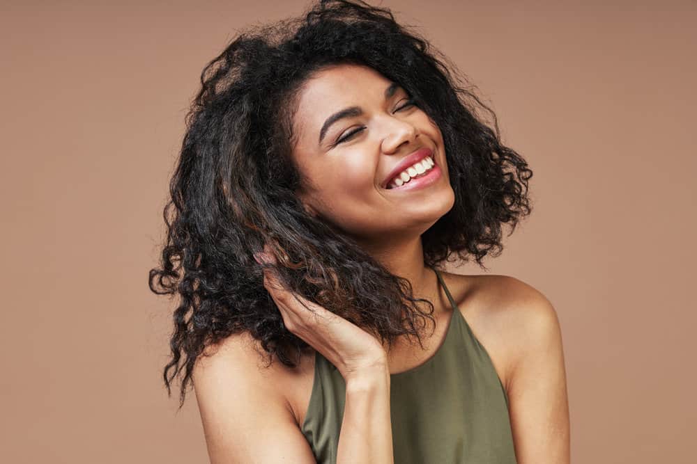 African American woman is using the curly girl method after wearing straightened hair and damaging her curls.