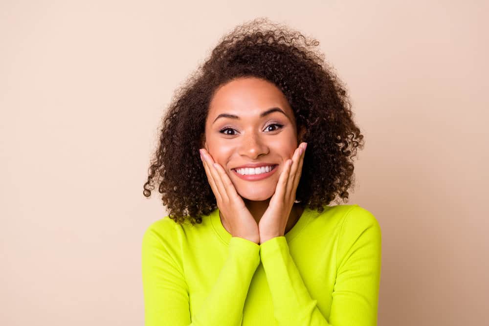 A pretty young black lady with curly hair feeling amazing after leaving the hair salon for a wash 'n go style.