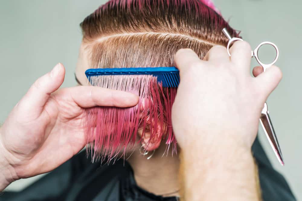 A lady has her hair dyed with pink and blonde hair dyes creating a unique style finished with olive oil.