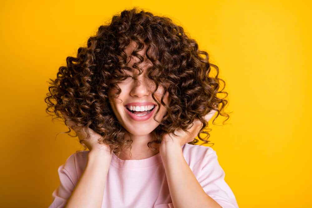 A Caucasian female poses after getting a perm kit installed in her thick hair and shows off her beautiful curly locks.