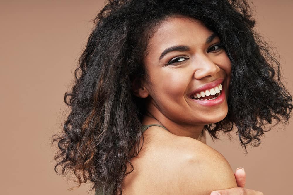 A cute light-skinned black girl wearing her thick hair curly styled with leave-in conditioner and argan oil.