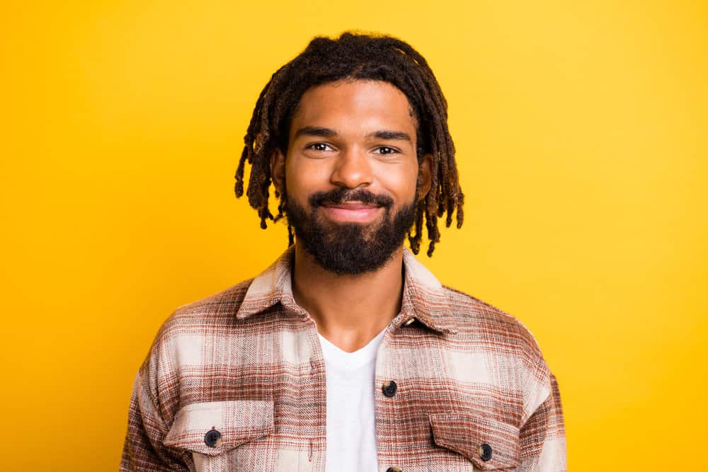 A bearded African American man wearing that has been seen in YouTube videos styling his mature ombre dreadlocks.