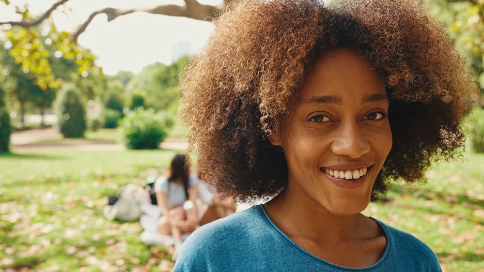 A black female with high porosity hair uses a hair care regimen that includes aloe vera juice on her thick strands.