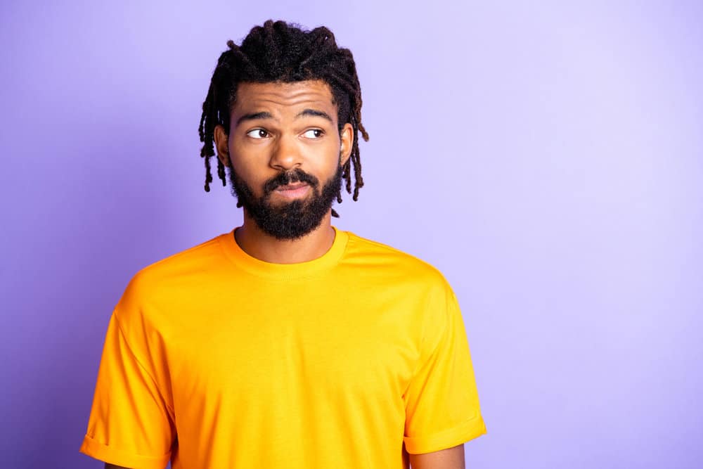 Black man wearing braided dreadlocks without faded sides, but it is a unique style or haircut.