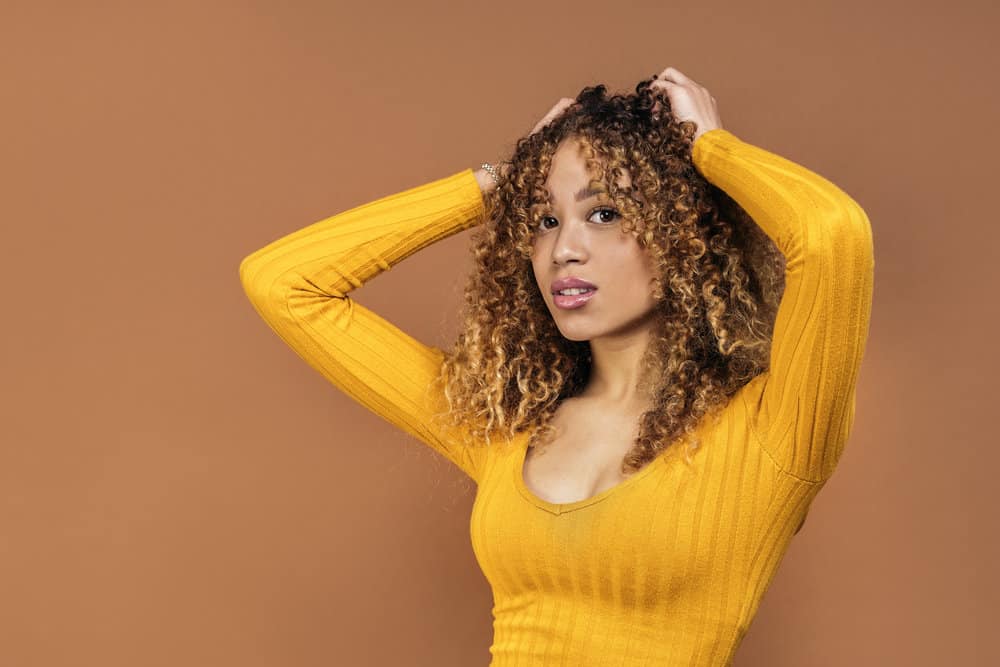 Black girl showing off a hair bleaching disaster after a DIY bleach job left her bleached hair uneven with orange tones.