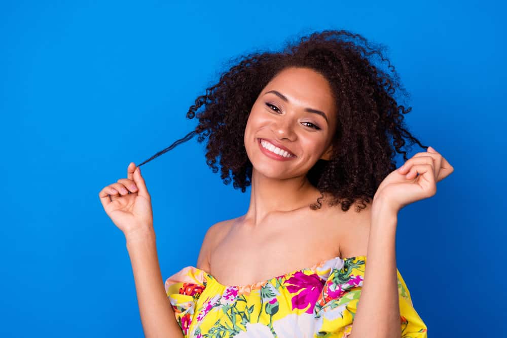 A stunning young girl with a dark brown hair color is concerned about split-ends after a keratin treatment for curly hair.