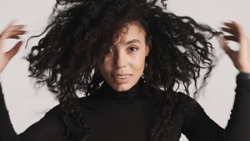 A woman used a blow dryer on her hair to add texture after using conditioning her curls with hair masks.