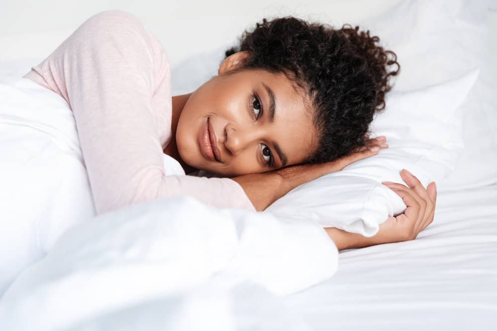 African woman with short curly hair wearing her hair secure in a protective style but without a satin scarf or bonnet.