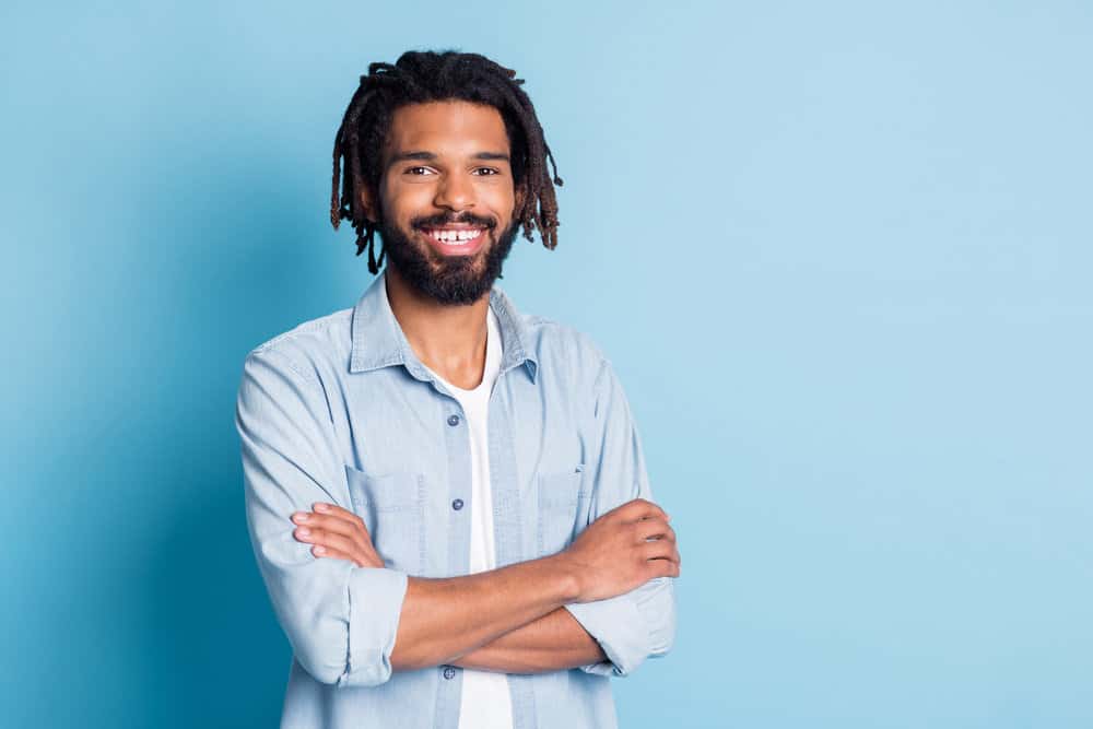 Cheerful African American man that's just a rap artist with the correct hair type to create locs with a classic undercut.