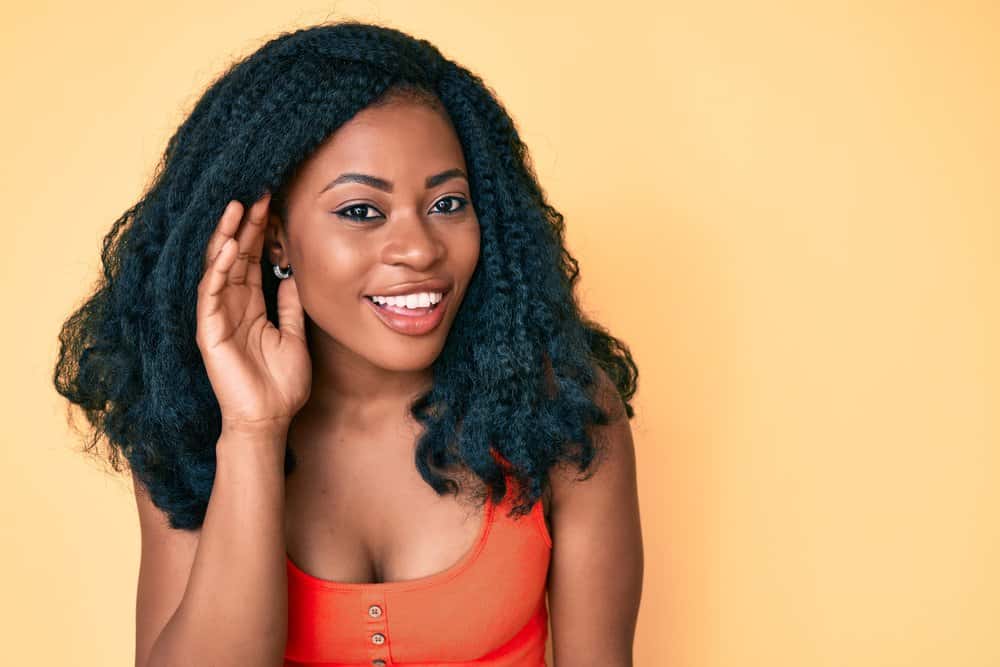 Beautiful African woman wearing natural curls styled with deep conditioner, frizz-free curl booster, and other products.