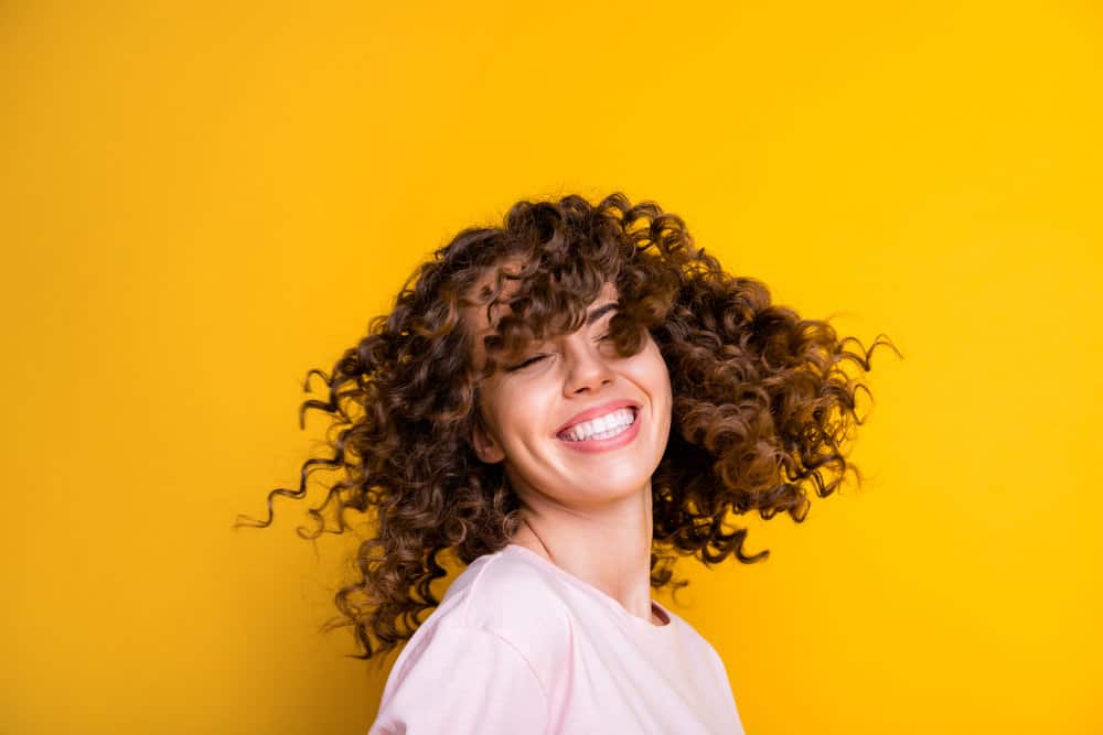 A young white girl wearing curls after wearing a straightened hairstyle without experiencing hair breakage.