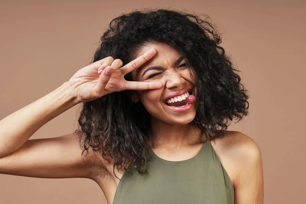 How to Get Curly Hair Back After Straightening It Too Much 8 Light-skinned black girl with a brown hair strand interweaved into her long hair strands.