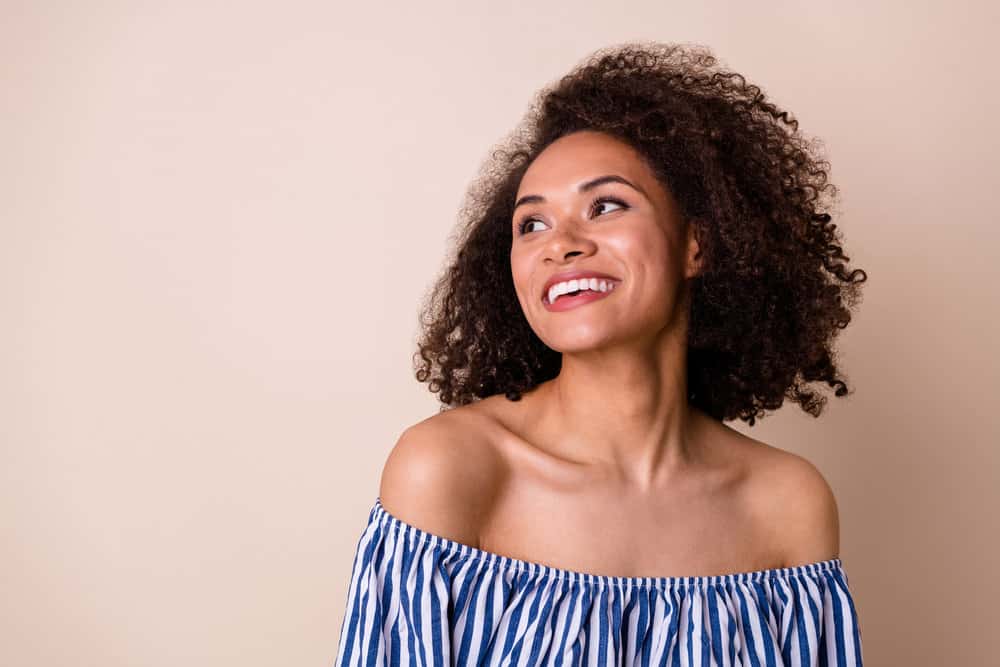 Positive female with a great smile wearing natural dyed curls styled with cream developer and natural color pigments.