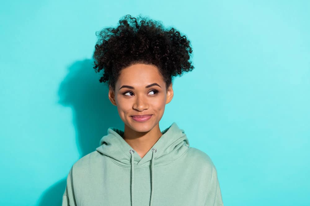 Cute young girl using coconut oil on her African American hair, making the hairstyling process easier.