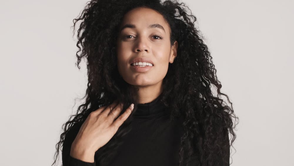 African American woman with thinner hair after using a straightening treatment to reduce some of the extra volume.