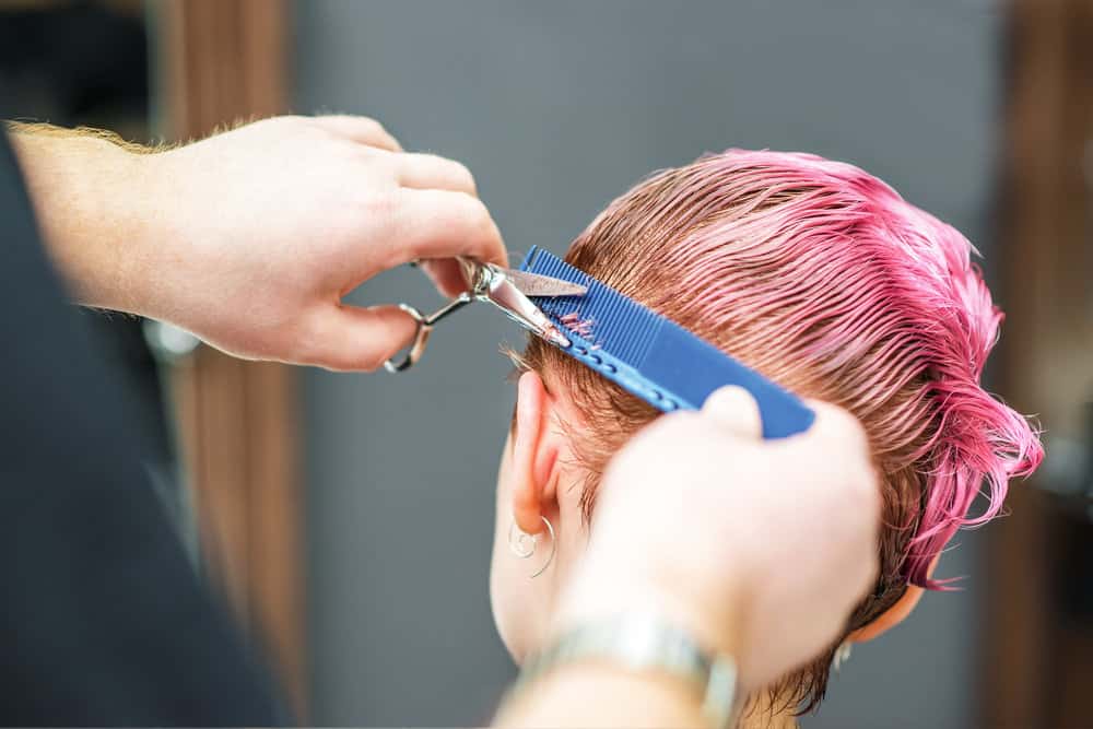 A young lady with naturally brown hair getting a haircut and pink hair color by a professional colorist.