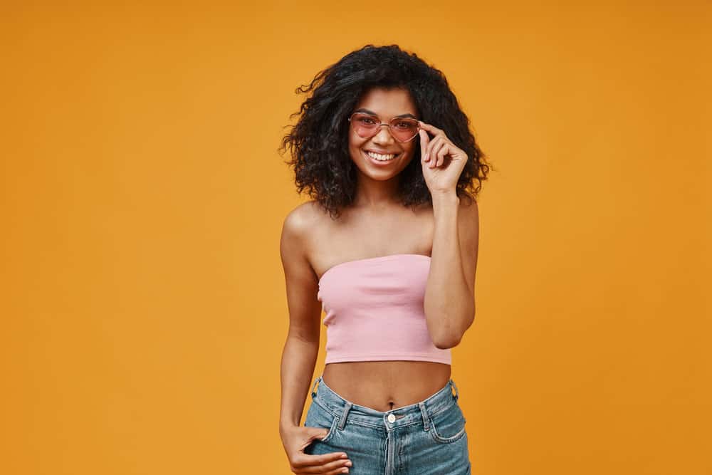 African American female with long hair treats her hair regularly with sulfate-free shampoo and conditioner.