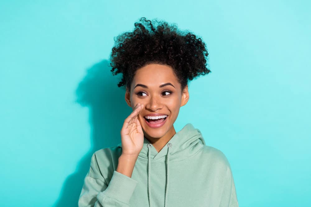 An excited African female with a clean scalp after using the perfect cleansing tool for curing dandruff.