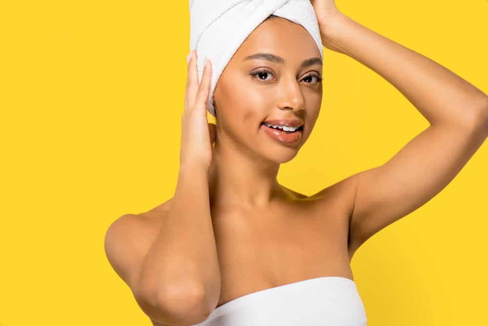 A cute black girl plopped her hair using a towel on a flat surface (like the bathroom counter).