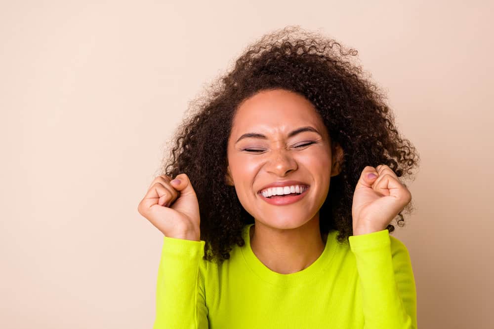 A young female with natural-looking makeup and curly hair styled with a natural haircare brand.