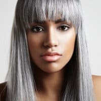 A young black woman with a natural gray hair color that trying to blend her salt and pepper hair with dyed hair.