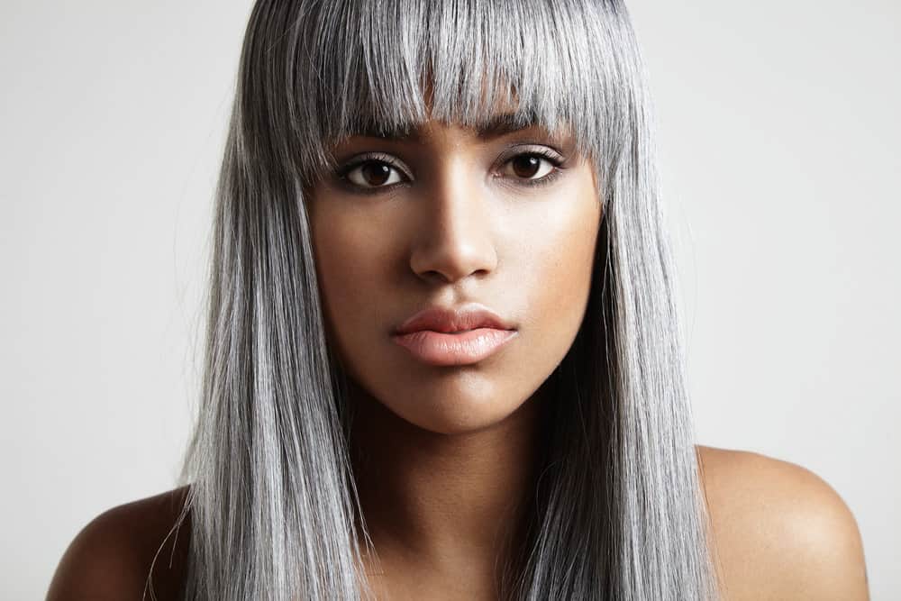 A young black woman with a natural gray hair color that trying to blend her salt and pepper hair with dyed hair.